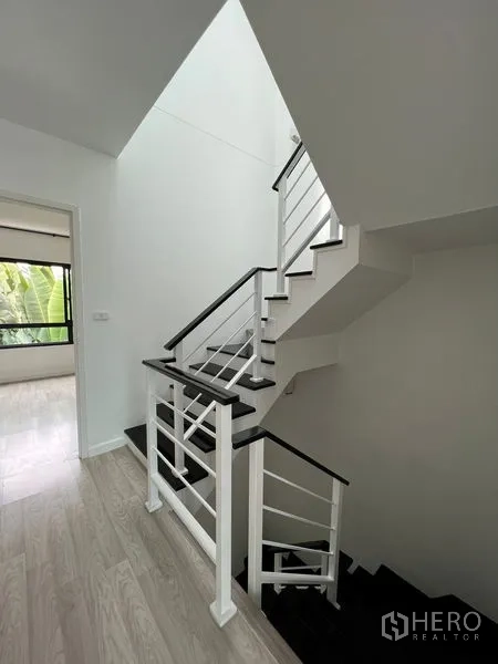 Townhouse for sale in Bang Kapi, Bangkok - Modern white-and-black staircase with metal railing in a bright hallway.