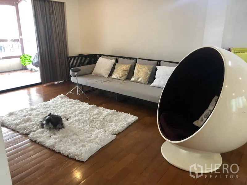 Condominium for sale - Open-plan lounge with long sofa, pod chair and sliding doors to terrace.
