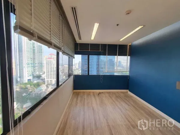 Office Space for rent in Watthana, Bangkok - Corner office with blue accent wall, wood floors and city views.