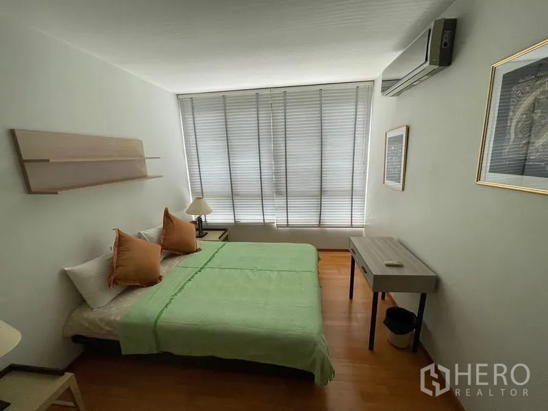 Condominium for sale in Khlong Toei, Bangkok - Second bedroom with desk, air conditioner and full-length window blinds.