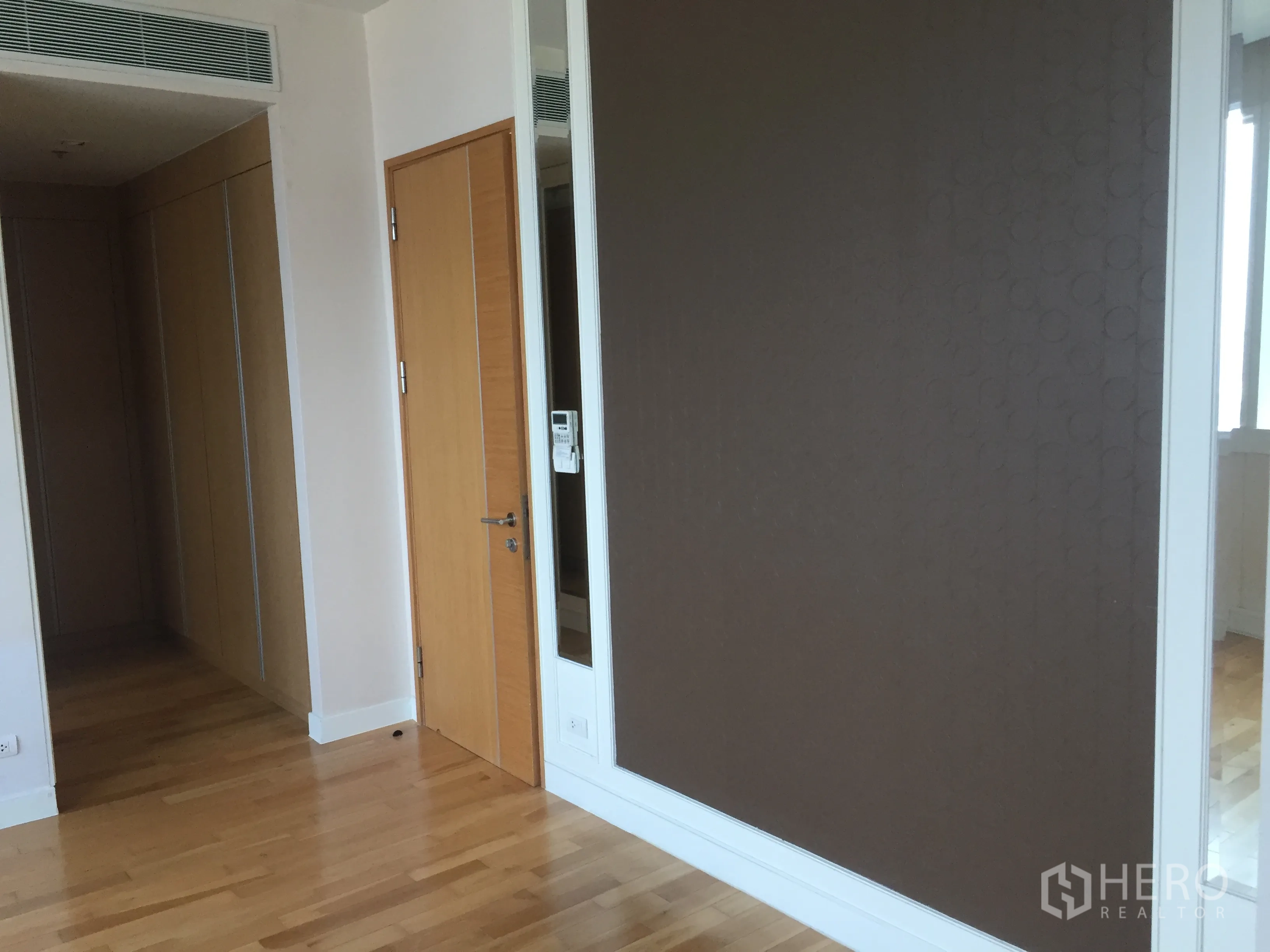 Condominium for rent in Khlong Toei, Bangkok - Hallway featuring tall wardrobes, wood door, and accent wall panels.