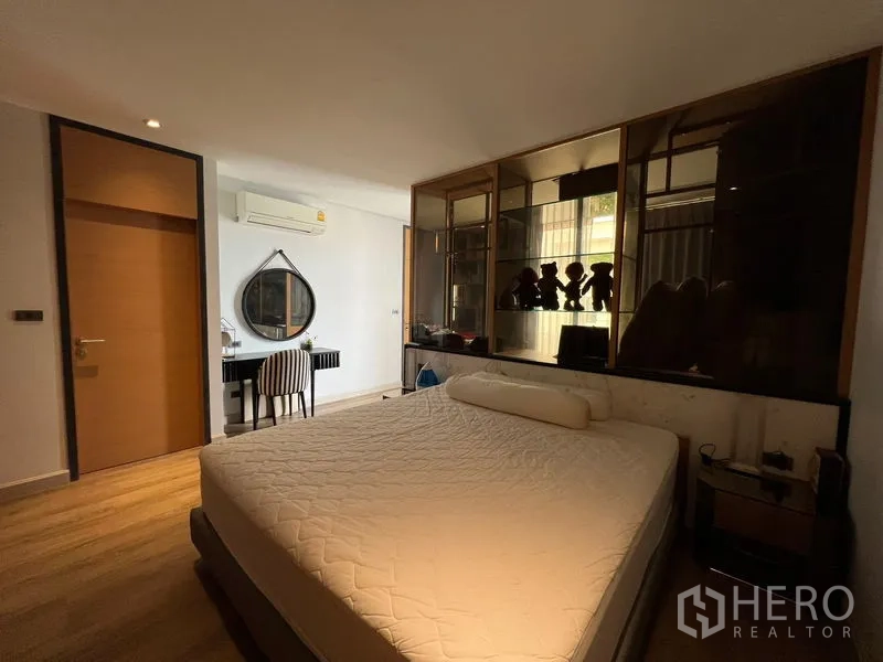 Townhouse for rent in Saphan Sung, Bangkok - Second bedroom with built-in display cabinet, vanity desk, and warm lighting.