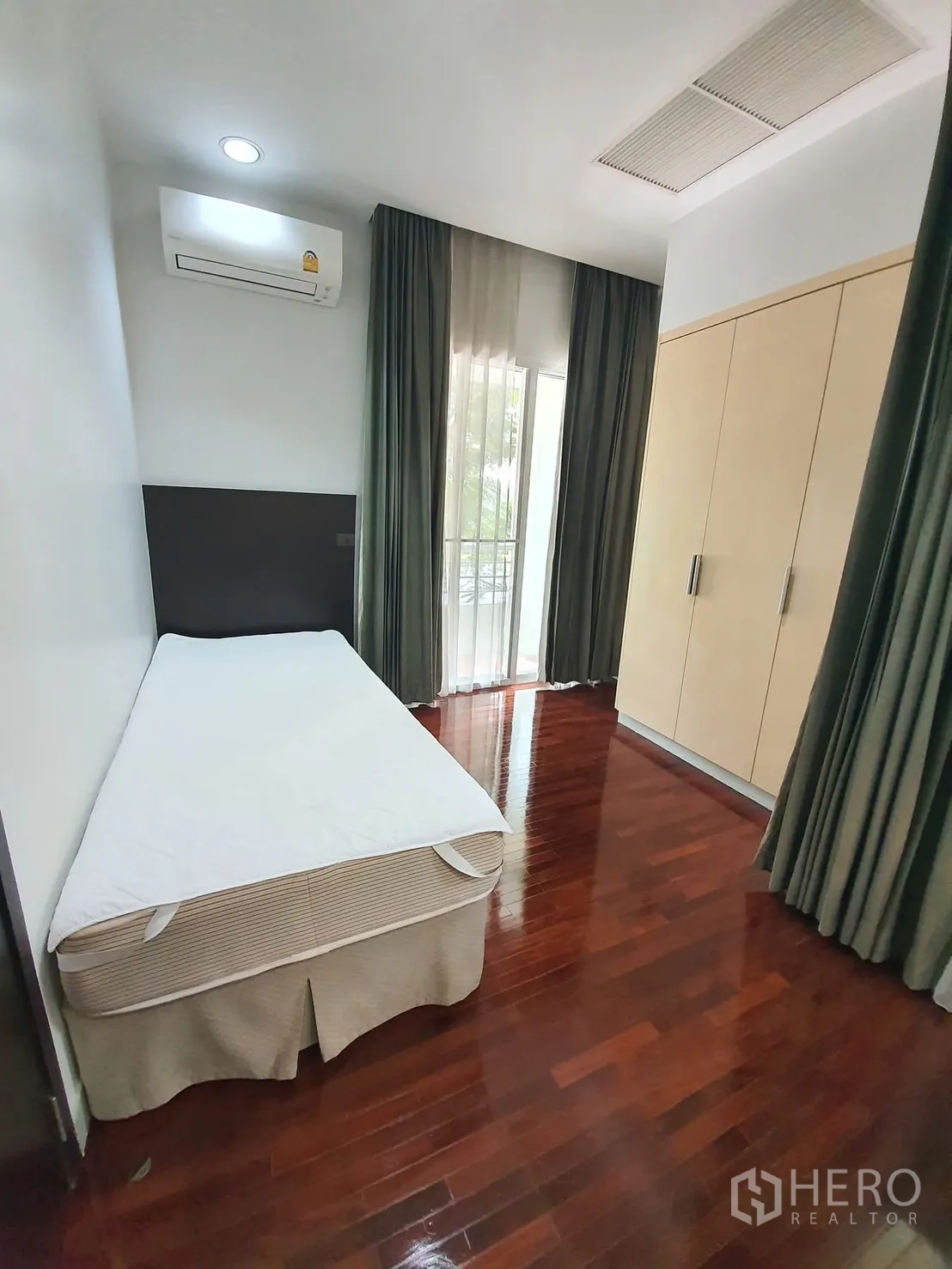 Detached House for rent in Wang Thonglang, Bangkok - Cozy bedroom with single bed, built-in wardrobe, hardwood floors, curtains, and air conditioner.