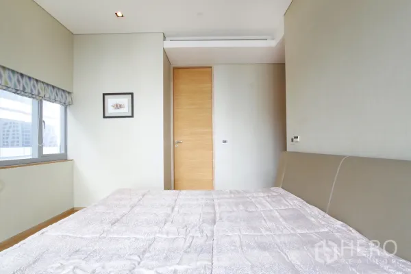 Condominium for sale in Bang Rak, Bangkok - Second bedroom with large window, patterned shade and light wood door.