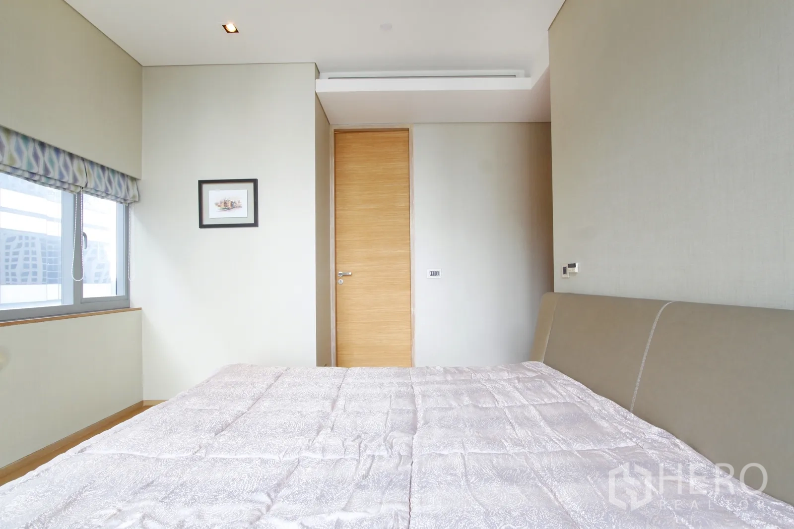 Condominium for sale in Bang Rak, Bangkok - Second bedroom with large window, patterned shade and light wood door.