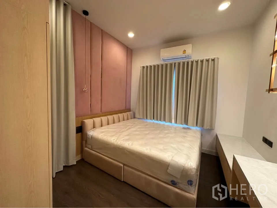 Detached House for rent in Bang Kapi, Bangkok - Cozy bedroom with padded headboard, pink accent wall, and curtains.