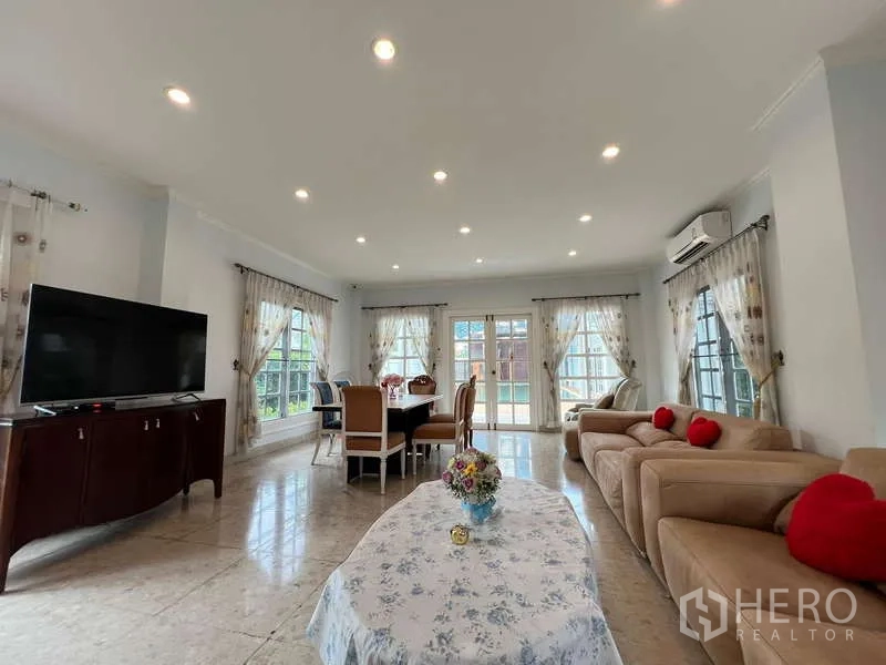 Detached House for rent in Bang Phli, Samut Prakan - Open-plan living and dining room with sofas, curtains, and TV, filled with light.