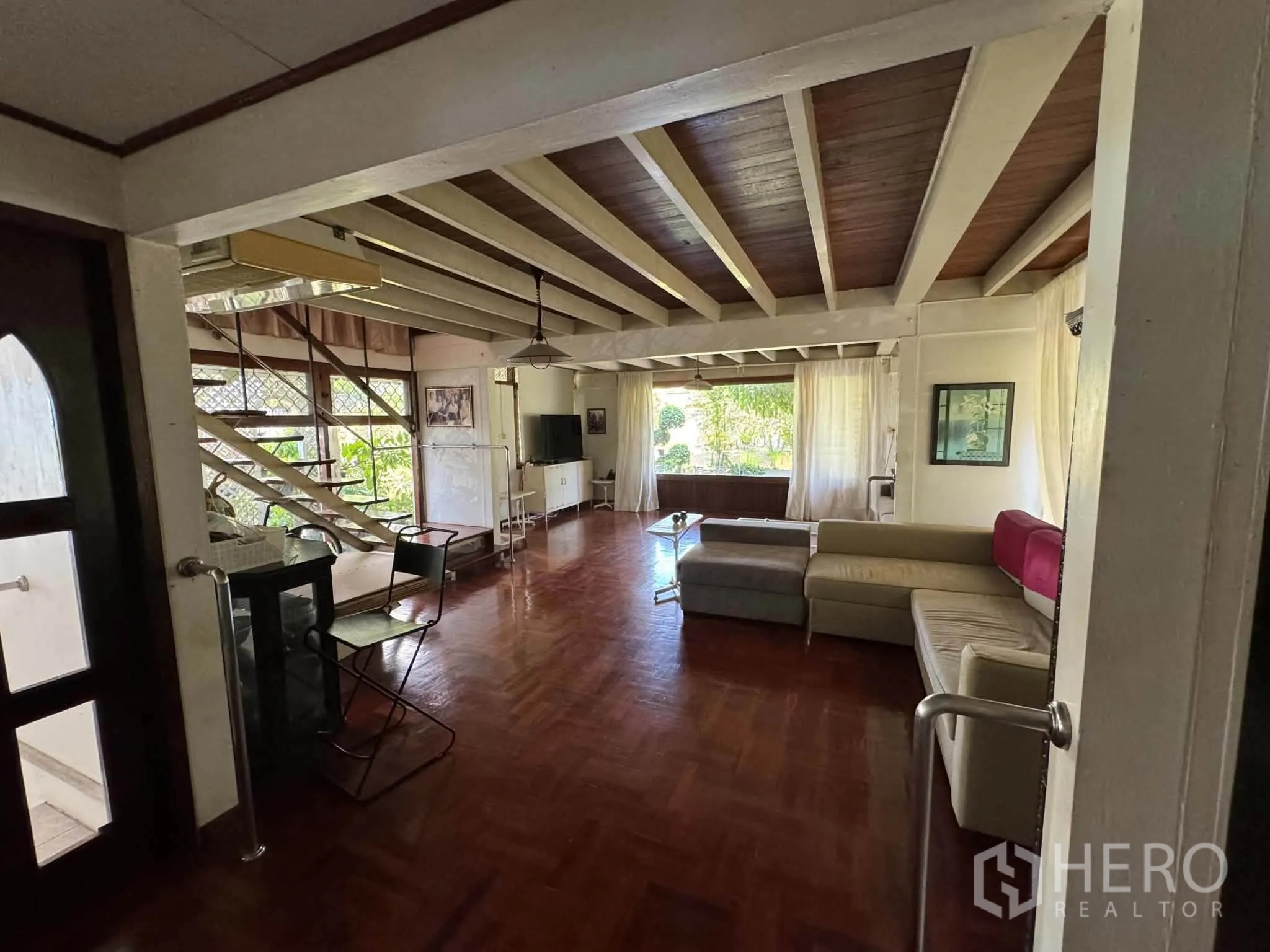 บ้านเดี่ยว for rent or sale in Mueang Samut Prakan, Samut Prakan - ห้องนั่งเล่นกว้าง โซฟาตัวยาว พื้นไม้ และบันไดเปิดโล่ง