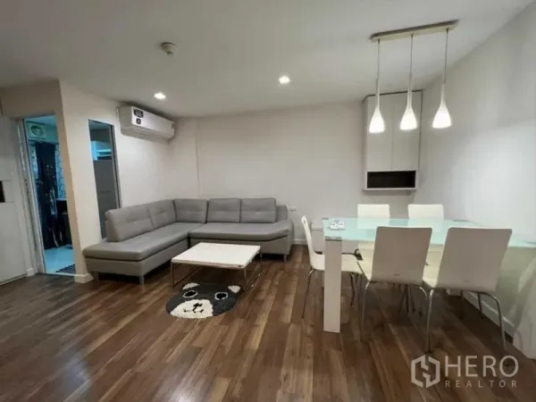 公寓 出售在Watthana, Bangkok - 开放式客餐厅，L型沙发、玻璃餐桌与吊灯