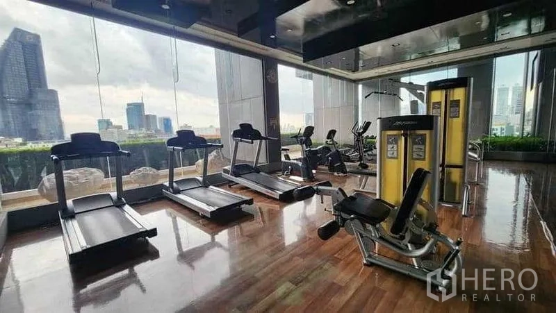 Condominium for rent in Khlong Toei, Bangkok - Fitness gym with treadmills and weights facing city views.