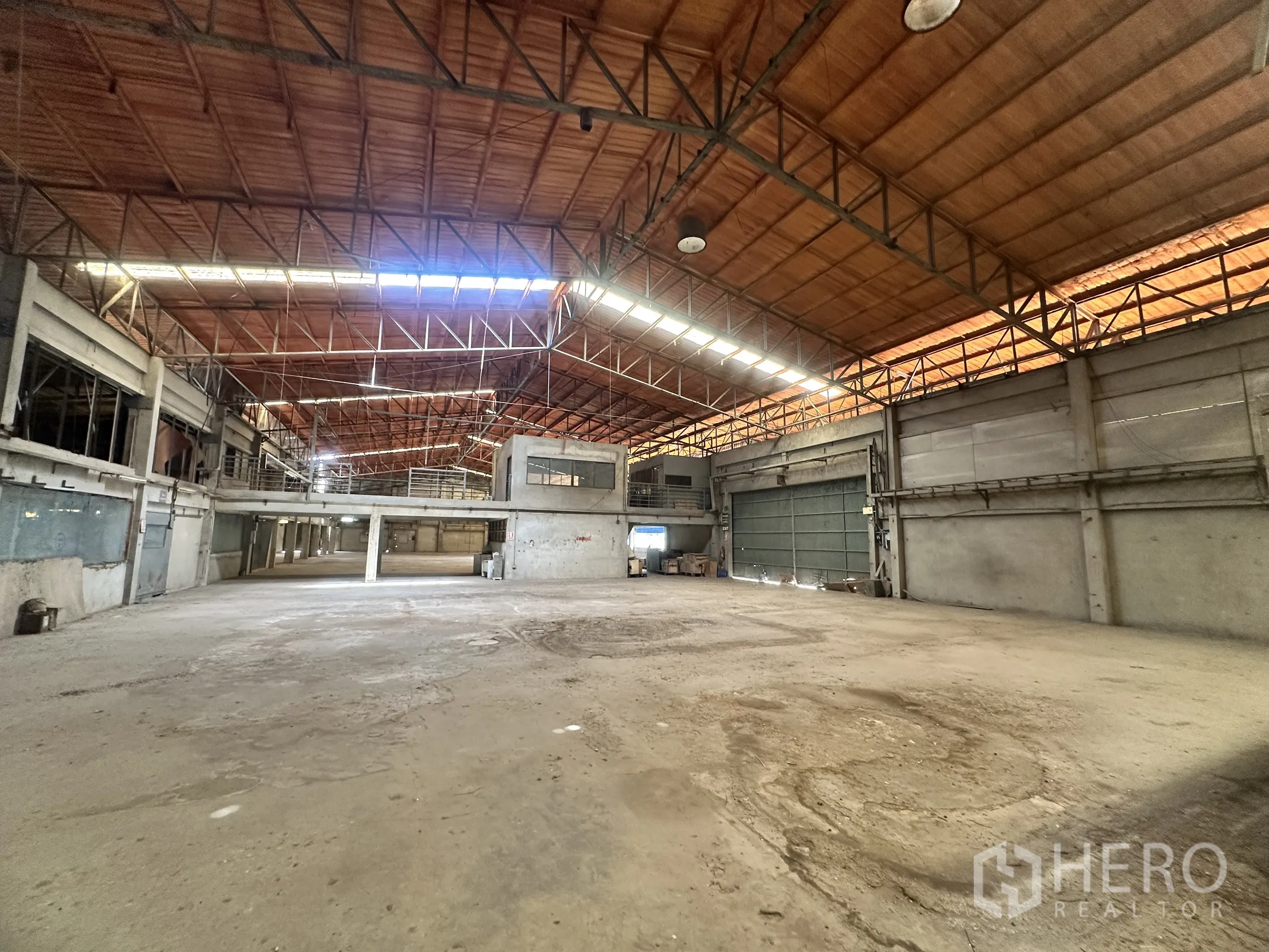 Factory for sale in Sai Noi, Nonthaburi - Production hall with high clearance, mezzanine platform, and sliding steel doors.