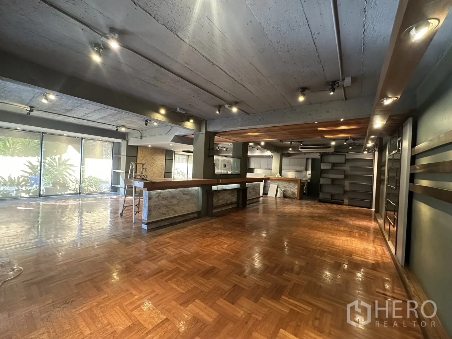 พื้นที่ขายของ for rent in Watthana, Bangkok - โถงภายในแบบเปิดโล่ง พื้นปาร์เกต์ เคาน์เตอร์บริการยาว ชั้นวาง และไฟราง
