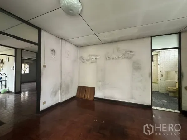 Detached House for sale in Phra Khanong, Bangkok - Secondary room with worn walls and doorway to a tiled bathroom, ready for renovation.