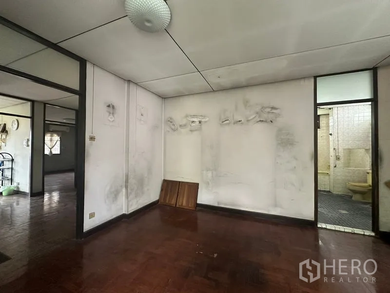 Detached House for sale in Phra Khanong, Bangkok - Secondary room with worn walls and doorway to a tiled bathroom, ready for renovation.