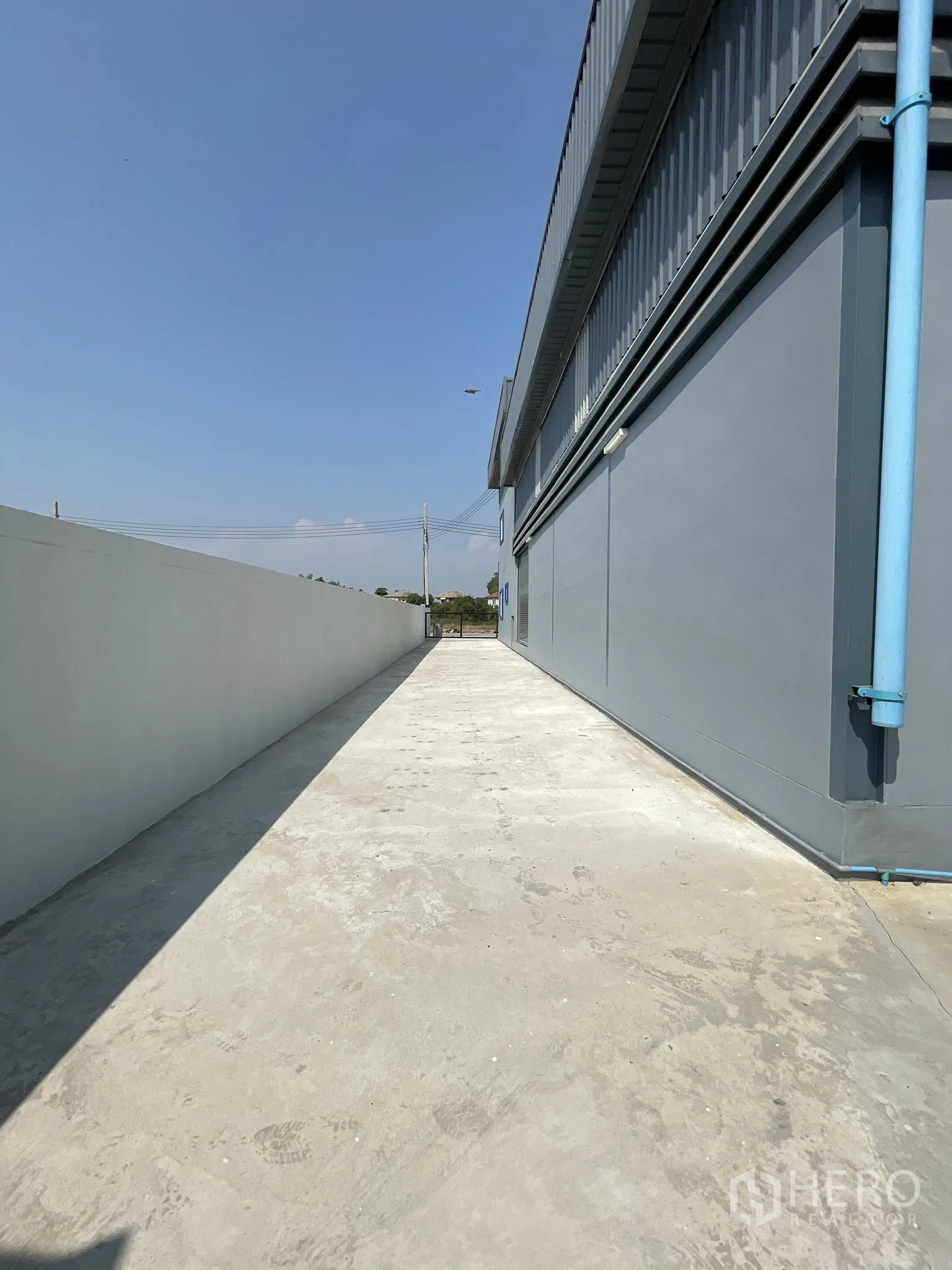 Factory for rent or sale in Bang Phli, Samut Prakan - Long side walkway beside the factory with boundary wall and exterior lighting.