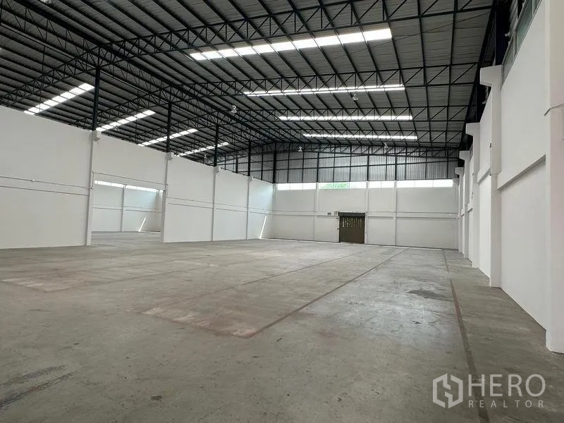 Warehouse for rent in Mueang Samut Prakan, Samut Prakan - Large storage space with natural light panels, white walls and smooth concrete slab.
