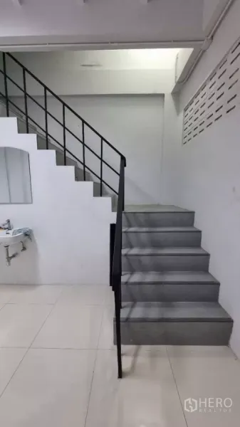 Townhouse for rent in Huai Khwang, Bangkok - Close-up of gray stairs with black metal railing and an under-stair sink.