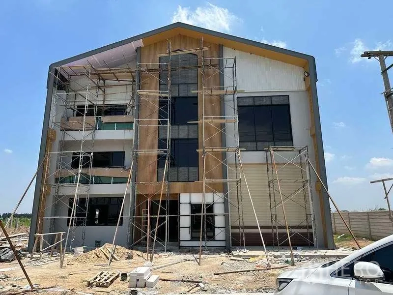 Factory for sale in Khlong Luang, Pathum Thani - Front facade of the factory with large glass panels, roller door and scaffolding during build.