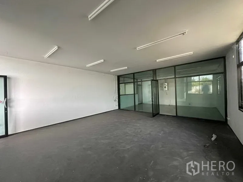 Warehouse for rent in Khlong Luang, Pathum Thani - Bright office room with fluorescent lighting and glass partitions.