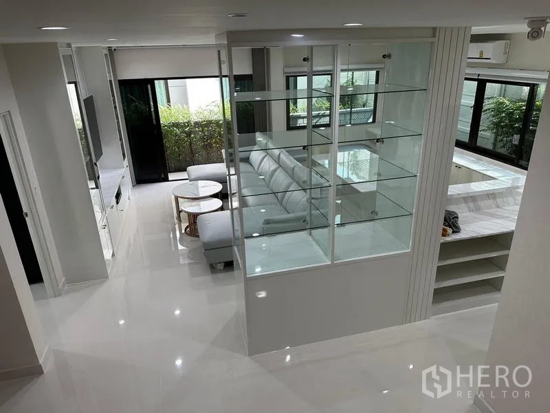 Detached House for sale in Saphan Sung, Bangkok - Open-plan view of the living area with glass display divider and sectional sofa.