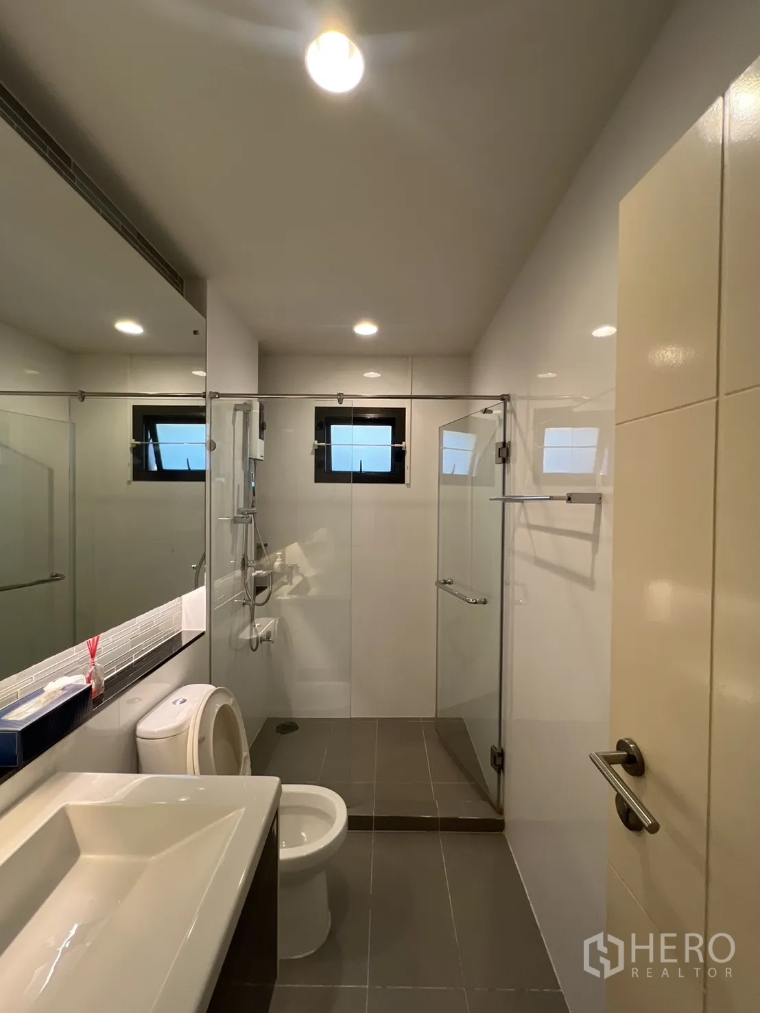 Detached House for sale in Bang Kapi, Bangkok - Modern bathroom with glass shower enclosure and large mirror.