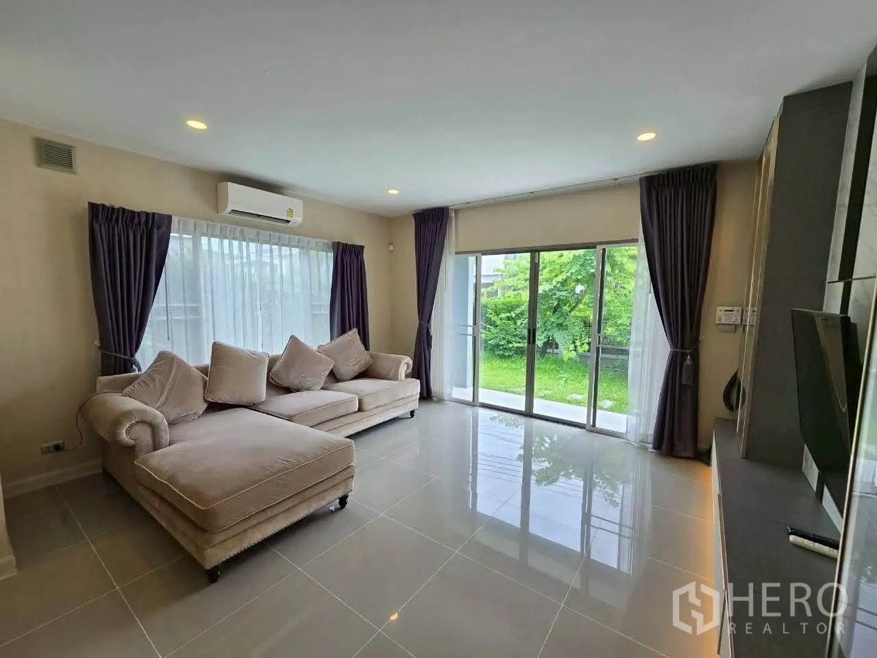 独栋房屋 for rent or sale in Lat Krabang, Bangkok - 明亮客厅，两组沙发与通向草坪的玻璃推拉门。