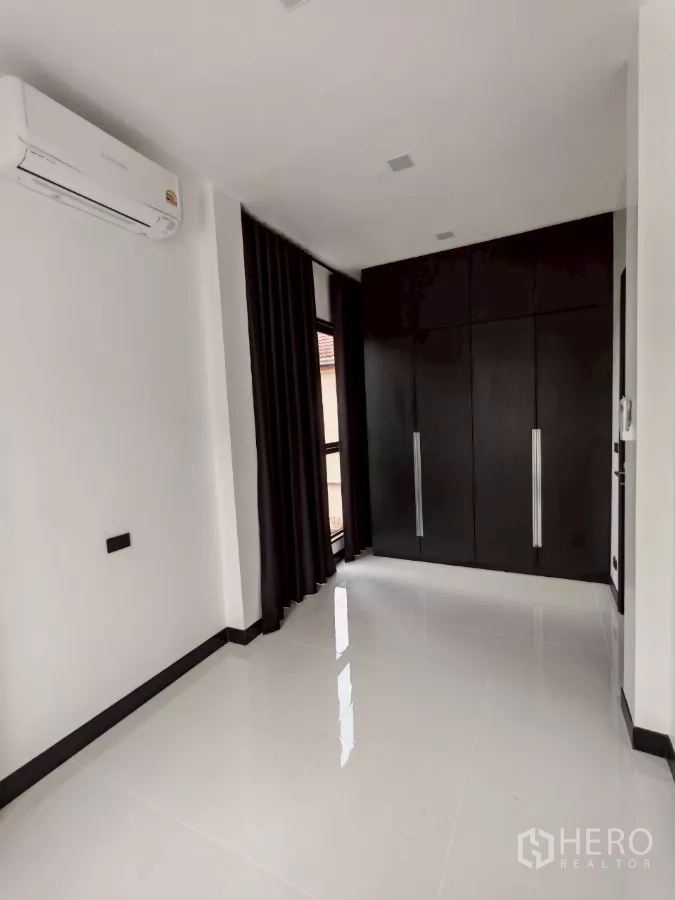Detached House for rent in Wang Thonglang, Bangkok - Bright room with air conditioner and built-in black wardrobe beside a window.