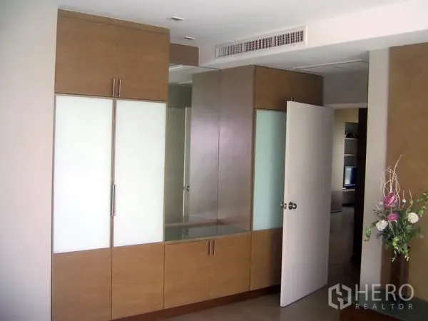 Condominium for rent in Khlong Toei, Bangkok - Bedroom with built-in wardrobes, large mirror vanity and concealed air-conditioning vent.
