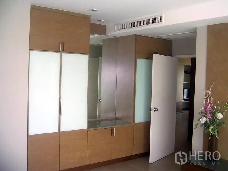 Condominium for rent in Khlong Toei, Bangkok - Bedroom with built-in wardrobes, large mirror vanity and concealed air-conditioning vent.