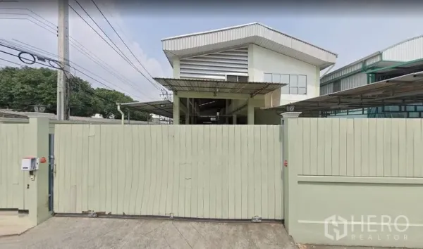 Warehouse for rent in Khan Na Yao, Bangkok - Front view of a gated warehouse with a high gable roof and secure perimeter wall in Khan Na Yao, Bangkok.
