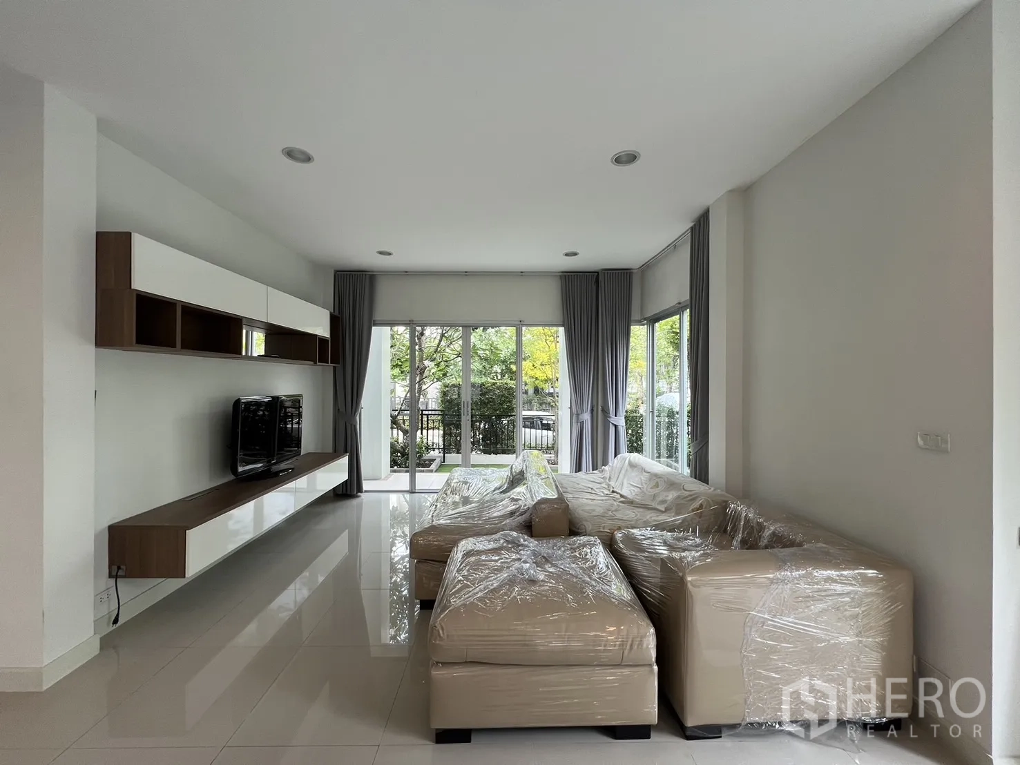 Detached House for rent in Saphan Sung, Bangkok - Long living space with floor‑to‑ceiling windows and curtains.