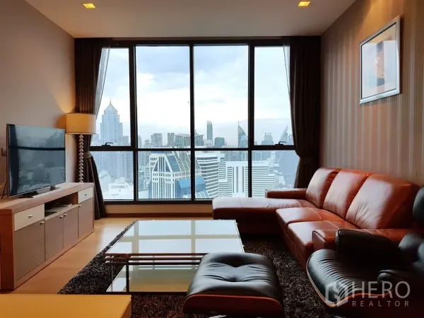 Condominium for rent in Watthana, Bangkok - Living room with leather sectional sofa, TV console and skyline windows