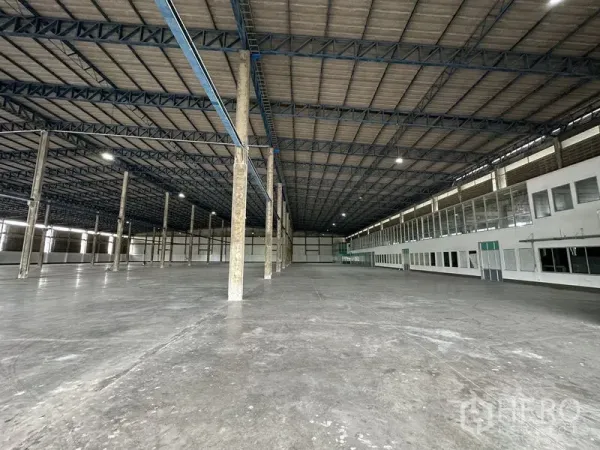 Factory for rent in Bang Sao Thong, Samut Prakan - Vast warehouse interior with 10 m high ceiling, concrete floor and a long side office block.