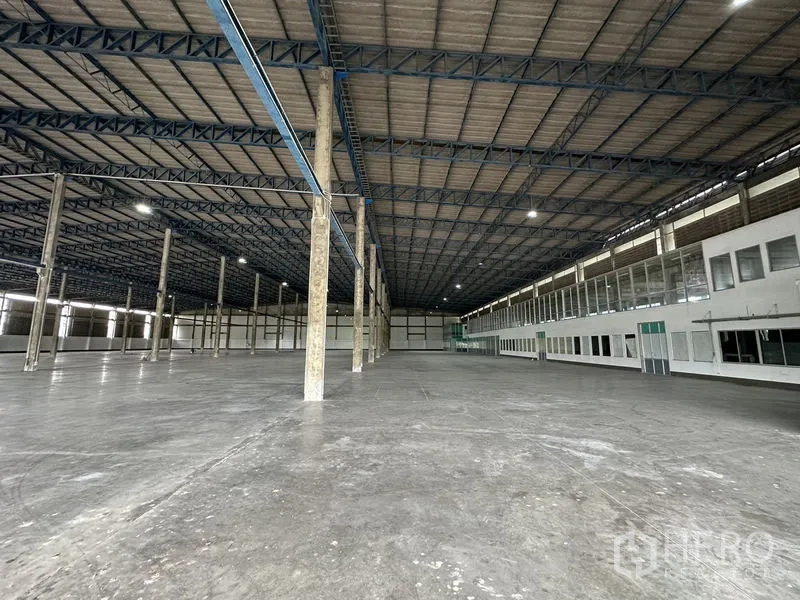 Factory for rent in Bang Sao Thong, Samut Prakan - Vast warehouse interior with 10 m high ceiling, concrete floor and a long side office block.