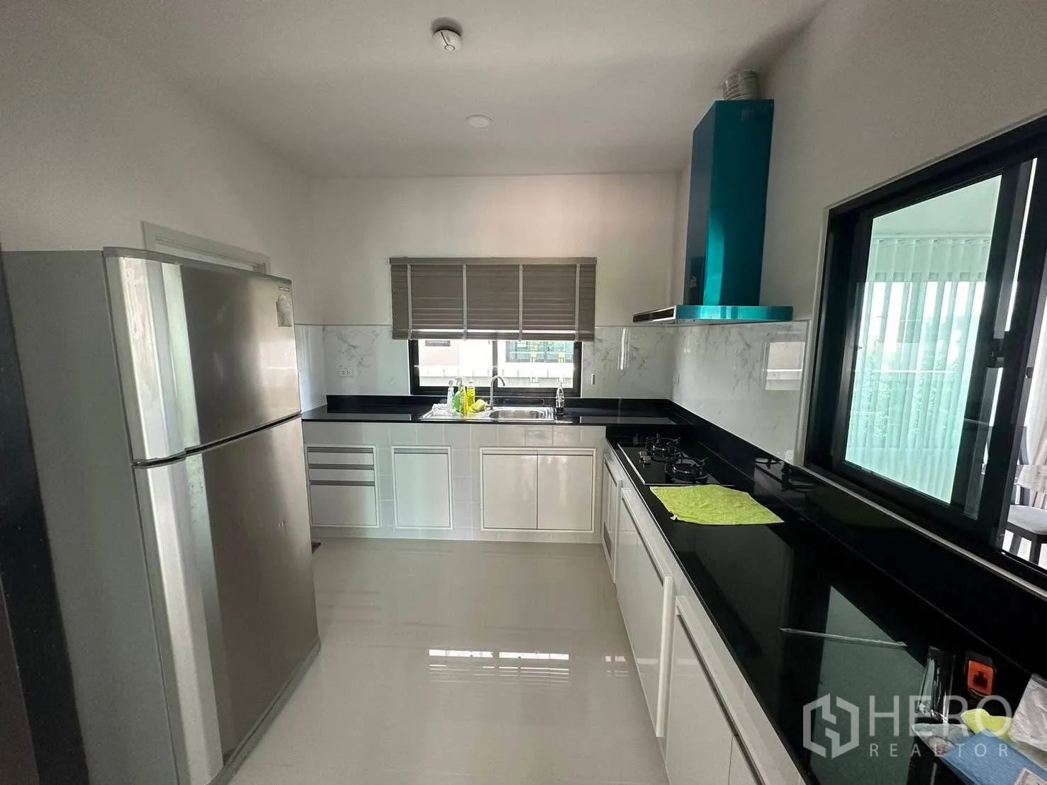 Detached House for rent in Bang Phli, Samut Prakan - Modern separate kitchen with white cabinetry, black stone countertops, gas hob, extractor and stainless‑steel fridge.