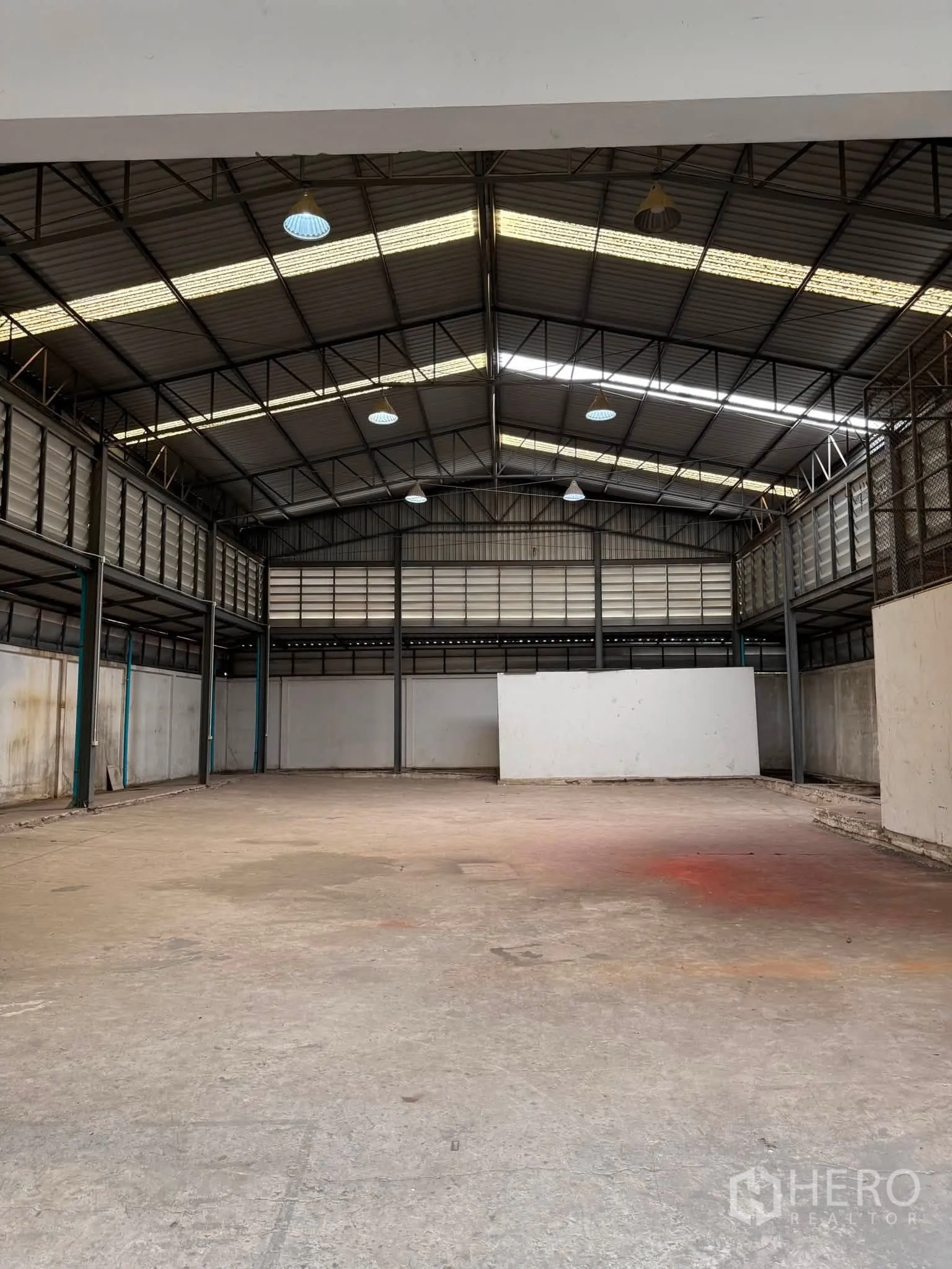 Warehouse for rent or sale in Phra Khanong, Bangkok - Clear-span storage space with high ceiling and hanging lights.