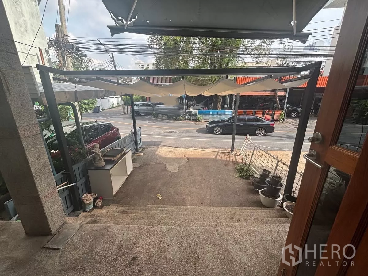 Shophouse for rent in Watthana, Bangkok - Shaded front terrace with steps overlooking the road and passing vehicles.