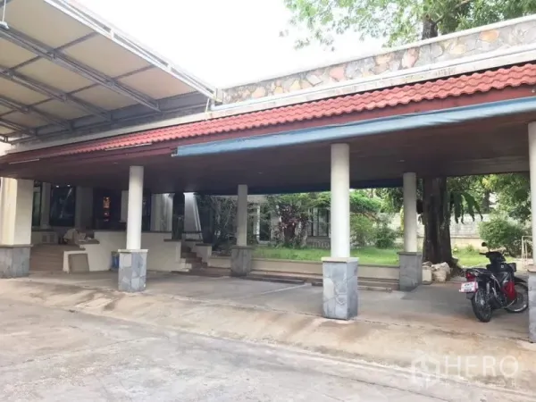 独立式住宅 出租在Bang Phli, Samut Prakan - 宽敞有顶车棚，红瓦屋顶与立柱，旁有车道与小草坪。