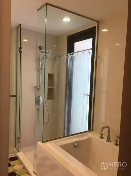 公寓 出租在Watthana, Bangkok - 浴室配玻璃淋浴间，旁边为浸泡浴缸与窗户。