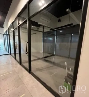 Retail Space for rent in Khlong Toei, Bangkok - Glass-front retail unit with black-framed floor-to-ceiling partitions and grey tile flooring.