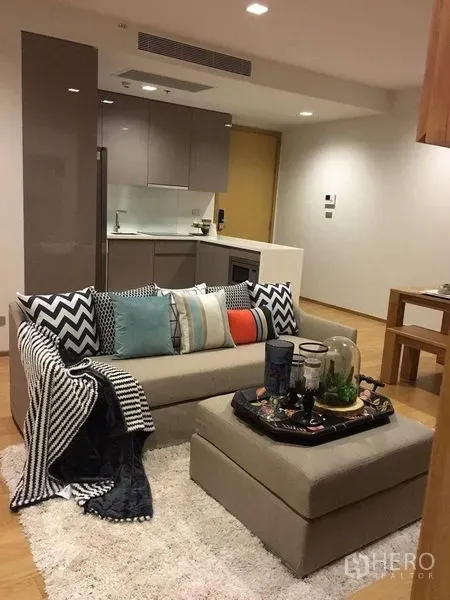 คอนโด ให้เช่าในWatthana, Bangkok - มุมห้องนั่งเล่นโอเพนแปลนกับโซฟาและครัวสมัยใหม่ในคอนโดสุขุมวิท