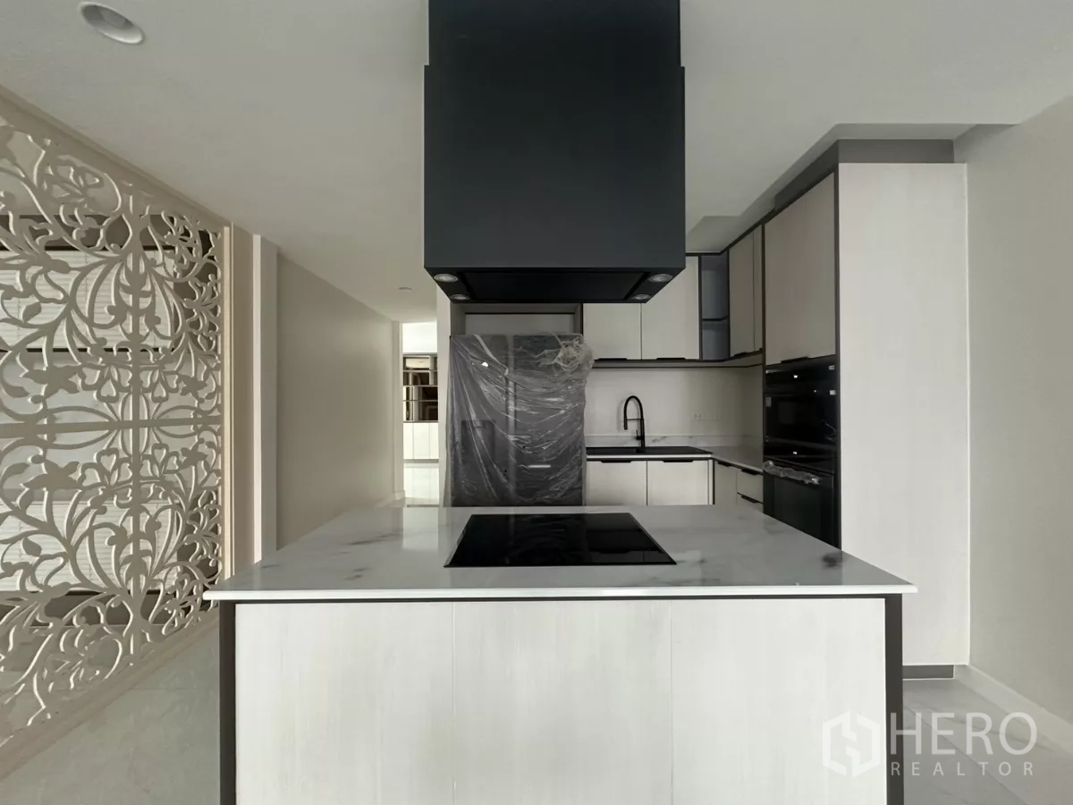 Townhouse for rent in Watthana, Bangkok - Contemporary kitchen with marble island, induction hob, and black range hood.