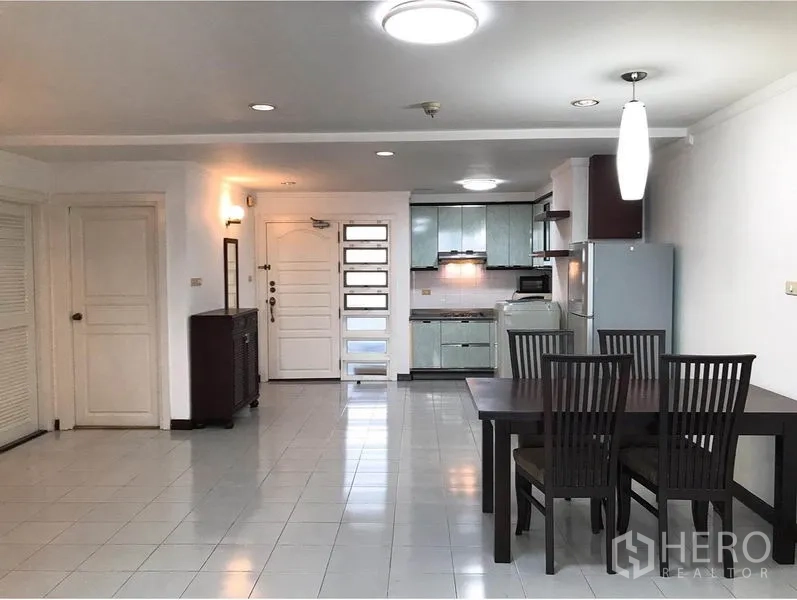 Condominium for rent or sale in Watthana, Bangkok - Open-plan dining and entry area leading to kitchen, with four-seat dining set and pendant light.