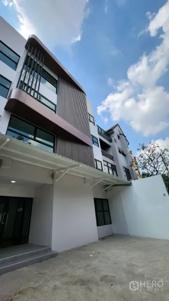 Home Office for rent in Chatuchak, Bangkok - Angled view of a modern multi-storey home office facade with large windows and a concrete forecourt.