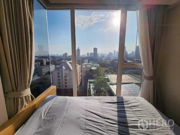 公寓 出租在Khlong Toei, Bangkok - 床边大玻璃窗外的城市天际线与阳光