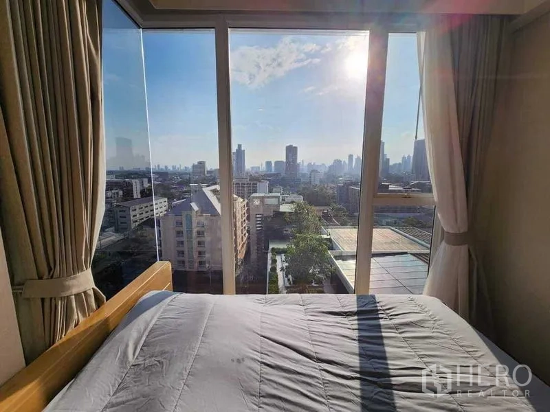 公寓 出租在Khlong Toei, Bangkok - 床边大玻璃窗外的城市天际线与阳光