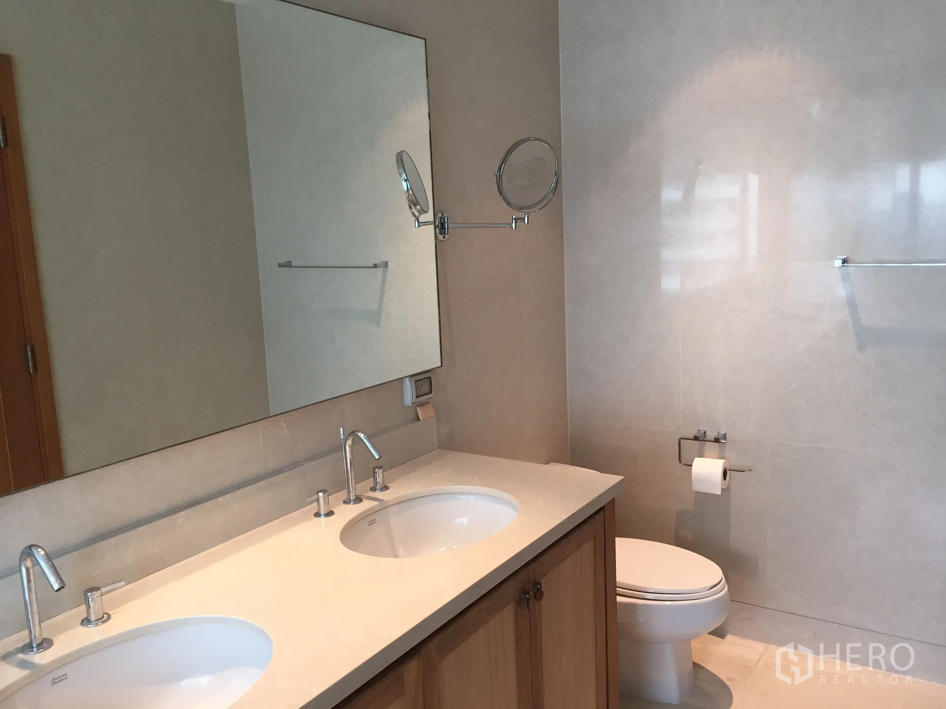 Condominium for rent or sale in Khlong Toei, Bangkok - Modern bathroom featuring double vanity sinks, large mirror, and ceramic toilet.