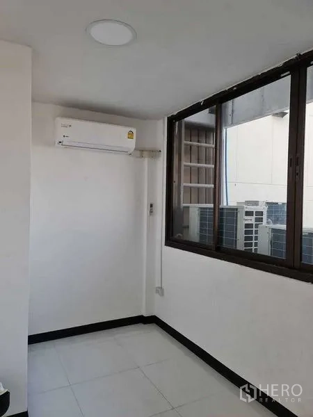店屋 出售在Watthana, Bangkok - 带窗与分体空调的小型办公室，可见外部机房区域。