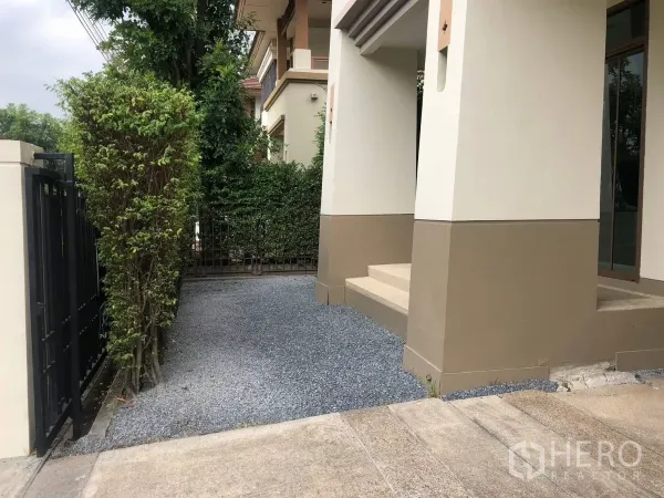 Detached House for sale in Bang Phli, Samut Prakan - Side driveway and covered porch beside the front gate with gravel surface.