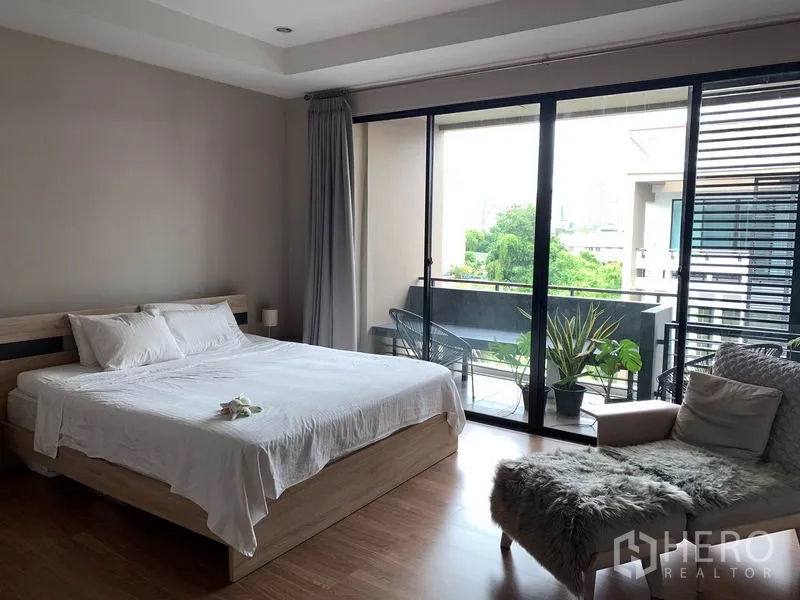 联排别墅 出租在Khlong Toei, Bangkok - 宽敞主卧，带阳台座椅和绿意景观。